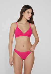 Conjunto de bikini rosa que incluye un sujetador triangular y una parte de abajo de tiro bajo. Fabricado con tela suave, con tirantes ajustables y costuras mínimas.