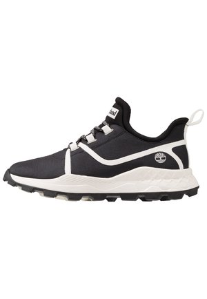 Sneaker atletica bianca e nera con lacci decorati, suola ammortizzata, linguetta sul tallone e logo sul lato, mostrata di profilo rivolta a sinistra.