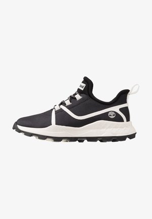Czarno-biały sportowy sneaker z wzorzystymi sznurowadłami, amortyzowaną podeszwą, pętelką na pięcie i logo z boku, pokazany z profilu zwrócony w lewo.