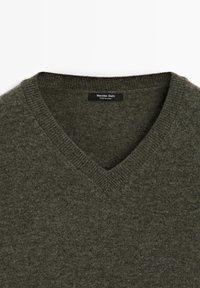 Pull vert foncé en laine à col en V avec col côtelé et étiquette Massimo Dutti à l'intérieur du col.