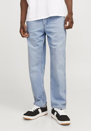 Hellblaue Jeans aus Denim mit geradem Schnitt und leicht ausgeblichenem Material, kombiniert mit schwarz-weißen Sneakers mit Gummisohle.