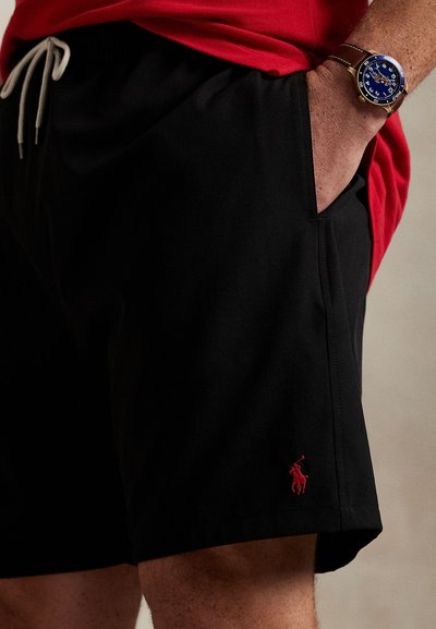 Juodos spalvos šortai iš lengvos medžiagos su elastinga juosmens juosta ir raišteliu. Kairėje kojoje mažas raudonas išsiuvinėtas logotipas.