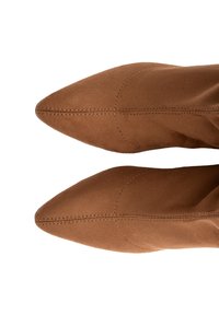 Brūni zamšs potītes zābaki ar norādītu purngalu, ar redzamām šuvēm un gludu tekstūru, attēloti no augšas.