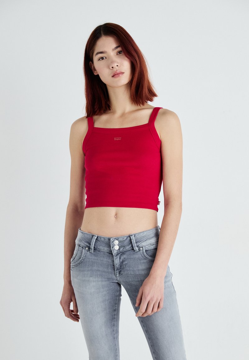 Top cropped vermelho canelado com decote quadrado e alças largas. Combinado com jeans de denim cinza claro com cintura alta e fecho de dois botões.