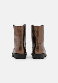 Botas de tobillo de cuero marrón con un acabado suave, puntera redonda y suela de goma negra. Presentan un forro suave en la abertura.