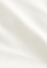 Tessuto di cotone strutturato color bianco sporco, che mostra una superficie liscia con sottili costine e morbide pieghe, indicando flessibilità e caduta.