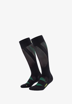 Kompressionsstrümpfe in Schwarz mit grünen Akzenten. Mit einem Mesh-Panel-Design, geripptem Textur und verstärkten Zehen- und Fersenbereichen.