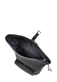 Črna tkaninska torba z zipom na vrhu, ki razkriva prostoren notranji prostor. Ima majhen zunanji žep z zapiranjem na sponko.