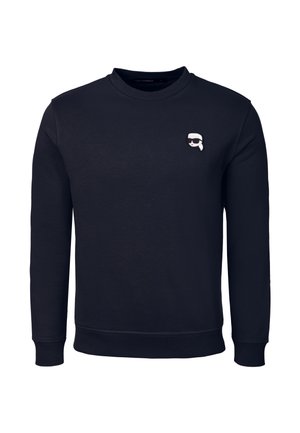Zwarte sweatshirt met lange mouwen en ronde hals, met een klein witte en zwarte cartoon gezicht met een zonnebril op de linkerborst.