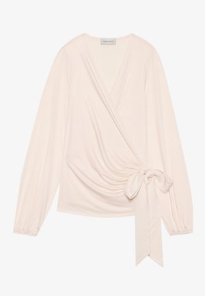 Wrap top in soft, light pink fabric. Features long sleeves, a tie at the waist, and gentle draping across the front.