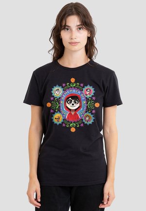Black cotton t-shirt featuring colorful graphic design with vibrant floral patterns and character illustrations, centered with "Remember Me" text.