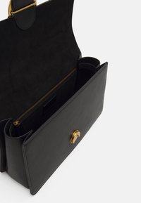 Čierna kožená kabelka s semišovým interiérom, s zlatou sponou a zipsovou vreckom, štruktúrovaný dizajn s dvojitými madlami.