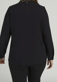 Svart långärmad blus med ett mönstrat krage och knappdetalj bak, med en avslappnad passform och slät textur.