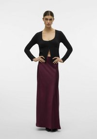 Svart långärmad croptop med spetskant och knappstängning, i kombination med en lång, bordeauxfärgad satinkjol med slät textur och figursydd design.