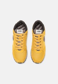 Pantofi sport galbeni, realizati dintr-un amestec de piele intoarsa si material mesh, cu varf rotund, design cu sireturi si un logo de marcă pe lateral.