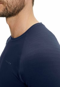 Marine sportshirt met gestructureerd streepdesign, ronde halslijn en smalle pasvorm. Logo zichtbaar aan de linkerkant, zichtbare stikseldetails.