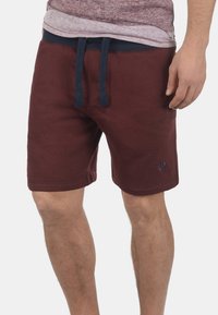 Pantalones cortos de polar burdeos con cinturilla ajustable. Cuenta con dos bolsillos laterales y un pequeño logo en el dobladillo inferior. Textura suave.