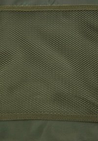 Olive green mesh fabric with diamond-shaped openings, attached to a smooth, matching base layer, bordered by a sturdy outer seam.
