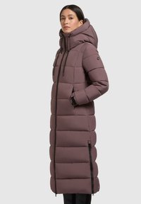 Palton lung tipat, într-o nuanță moale de mov, cu un design căptușit, guler înalt, glugă și accente de fermoar negre. Include buzunare laterale pentru confort.