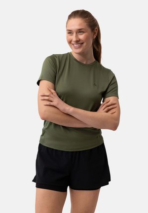 T-shirt de sport olive à manches courtes avec un col rond et un logo. Associé à un short de sport noir, mettant en valeur une silhouette ajustée.