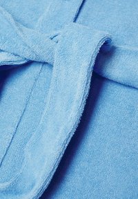Ceinture de peignoir en éponge bleu clair nouée à l'avant du peignoir, montrant la texture du tissu et les coutures.