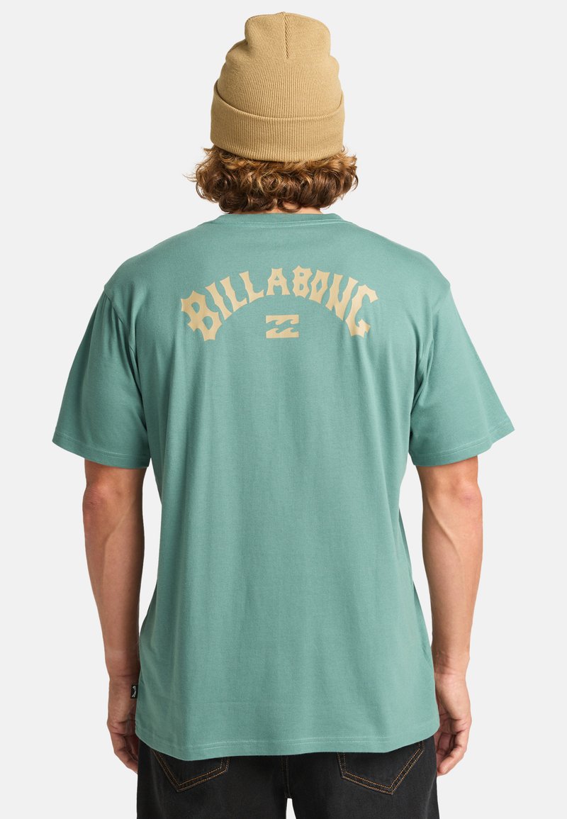 Camiseta de manga corta de color verde menta con el logotipo "Billabong" en color beige impreso en la parte posterior. Tejido suave con un ajuste relajado, diseño simple y cuello redondo.