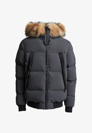 Dikke grijze jas met een nepbont capuchon, voorrits, rode accentsteken en geribbelde manchetten. Beschikt over twee zijzakken.