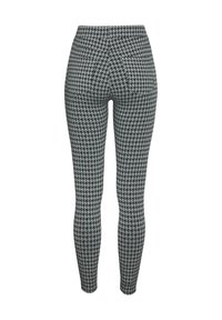Leggings visoko strukirane s crno-bijelim houndstooth uzorkom, izrađene od rastezljivog materijala s glatkom teksturom.