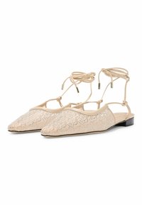 Beżowe płaskie buty z ostrym noskiem, z teksturowaną cholewką ozdobioną srebrnymi cekinami orazwiązaniem na kostce z akcentami w kolorze złotym.