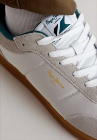 Zapatillas Pepe Jeans con parte superior de cuero blanco y detalles en ante gris, cordones blancos, detalles en color teal y suela de goma con logotipo dorado.