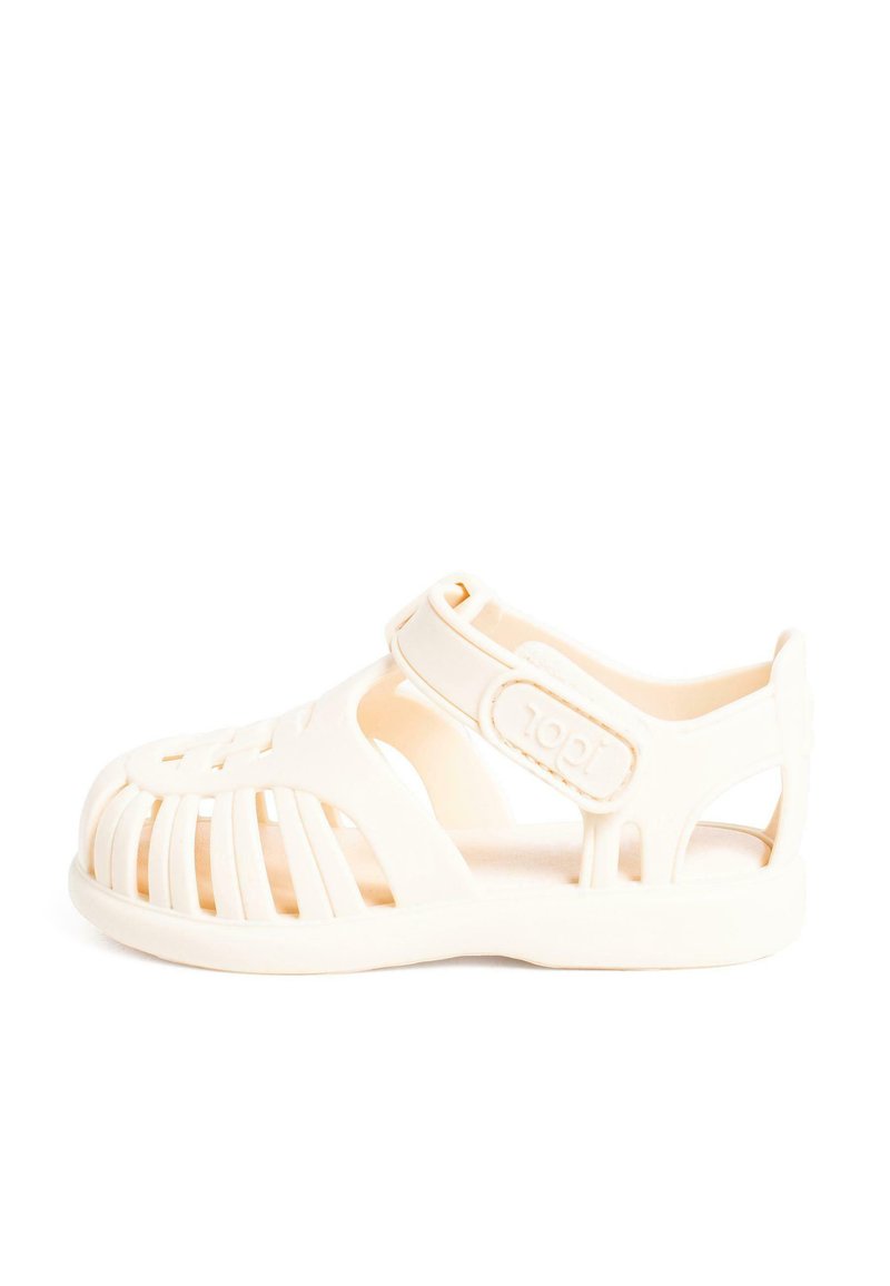 Sandal in gomma beige chiaro con punta chiusa, lati aperti e cinturino regolabile caratterizzato da un design testurizzato con ritagli.