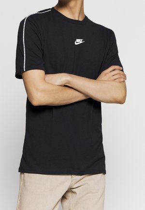 T-shirt in cotone nero con maniche corte, caratterizzato da un logo Nike bianco sul petto e strisce bianche sui lati delle spalle.