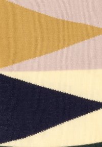 Stickad tyg med geometriska mönster av senapsgul, rosa, krämfärgad och marinblå trianglar i olika bredder och texturer.