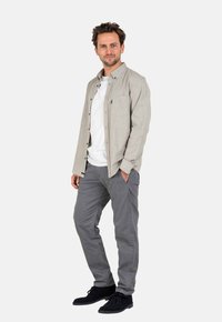 Light gray button-up shirt over a white t-shirt, paired with gray pants and black shoes. Smooth fabric with a casual fit.