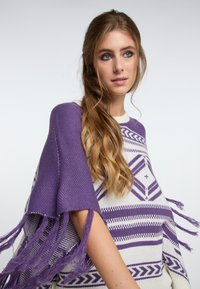 Poncho mov și crem cu modele geometrice, având detalii cu franjuri pe mâneci și o textură tricotată, lejeră și confortabilă.