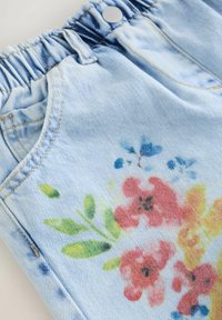 Ljusblå denimshorts med elastiskt midjeband, med ett blommönster i rött, gult och blått, samt framfickor.