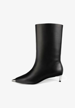 Mustan nilkkapituinen nahkasaapas, jossa on terävä hopeinen kärki ja matala hopeinen korko valkoista taustaa vasten.