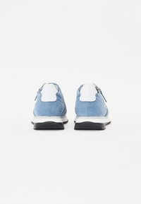 Kék textil sportcipők fehér részletekkel, zipzáras zárással, fekete gumi talppal és elegáns, lekerekített formával.