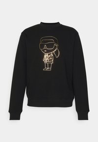 Felpa nera con una illustrazione in contorno dorato di un personaggio con occhiali da sole e coda di cavallo, che indossa un completo. Tessuto morbido.
