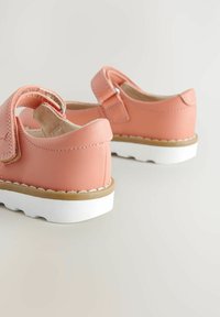 Różowe syntetyczne skórzane buty z rzepem, biała gumowa podeszwa i subtelne detale przeszycia. Zaokrąglony design palców.