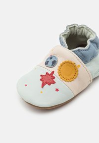 Myke skinn slip-on sko med en lys blå og pastellfargepalett. Har applikasjoner av planet, sol og stjerne. Teksturert overflater og elastisk åpning.