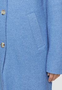 Cappotto di lana blu chiaro con chiusura a bottoni e tasche laterali, con una finitura morbida e testurizzata e maniche lunghe.