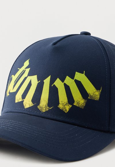 Καπέλο μπέιζμπολ σε ναυτικό μπλε με καμπύλη γείσο, διακοσμημένο με μεγάλα κίτρινα γράμματα γοτθικού στυλ στο μπροστινό μέρος.