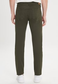 Olijfgroene katoenen broek met een rechte pasvorm, twee achterzakken en een gestructureerde afwerking, gecombineerd met witte sneakers.