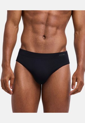 Muskelöser männlicher Oberkörper trägt schwarze Falke-Unterhosen mit sichtbarem Taillenbundlogo vor weißem Hintergrund.