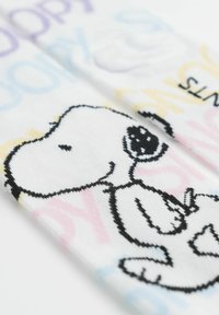 Calzini bianchi con un contorno nero di un cane dei cartoni animati, con testo e dettagli nei colori pastello blu, giallo e rosa. Texture del tessuto morbida.