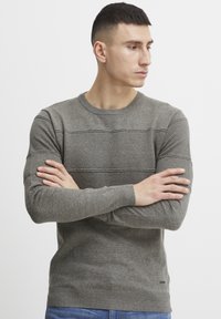 Pulover gri tricotat cu modele texturate și secțiuni netede, guler rotund, mâneci lungi și tivuri ribbate.