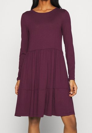 Robe à manches longues de couleur violet profond, confectionnée dans un tissu doux avec un corsage ajusté et une jupe évasée à volants. Encolure ronde simple, sans motifs.