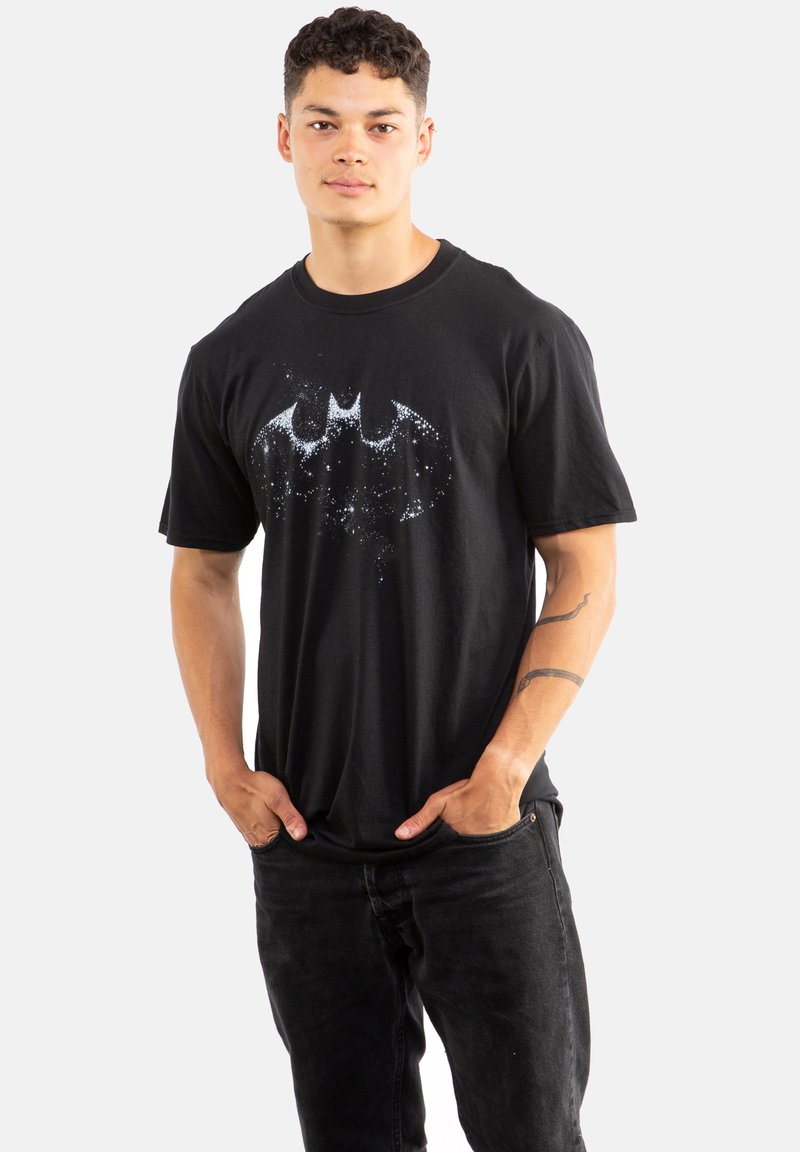 Black cotton t-shirt featuring a white, glittery Batman logo. Classic fit with short sleeves and a crew neckline. Model wears black jeans.