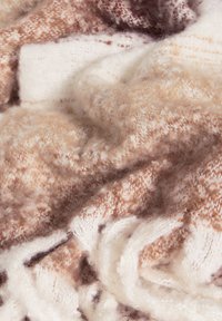 Zachte, gemêleerde deken in beige, bruin en crème tinten, met een gezellige breipatronen en franjes aan de randen. Dikke en warme stof.